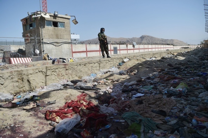 A Taliban fighter stands guard at the site of the August 26 twin suicide bombs, which killed scores of people including 13 US troops, at Kabul airport on August 27, 2021. (Photo by WAKIL KOHSAR/AFP via Getty Images)