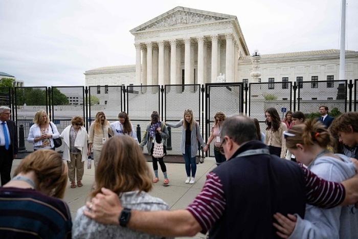 Pro-life demonstrators pray near the fence now ringing the US Supreme Court on May 5, 2022. (Photo by JIM WATSON/AFP via Getty Images)