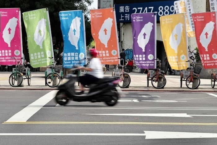 A motorcyclist rides past a display of pro-Taiwan independence flags in Taipei. (Photo by Sam Yeh / AFP via Getty Images)