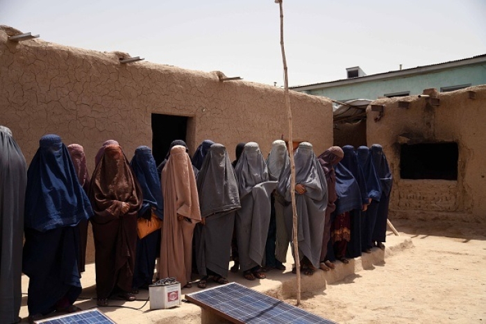 Burqa-clad women in Afghanistan are seen outside a shampoo and soap factory in Kandahar on July 30, 2022. (Photo by JAVED TANVEER/AFP via Getty Images)