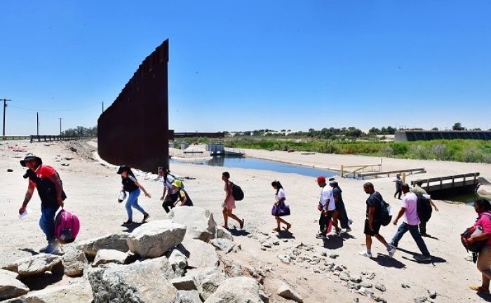 Migrants cross into the US from the Mexico through a gap in the border wall separating the Mexican town of Algodones from Yuma, Arizona, on May 16, 2022. (Photo by FREDERIC J. BROWN/AFP via Getty Images)