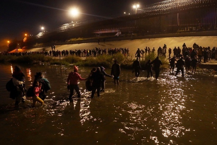 Migrants travelling in a caravan of more than a thousand people from Nicaragua, Peru, Ecuador, Colombia, Venezuela and the Dominican Republic cross into El Paso, Texas on December 11, 2022. (Photo by HERIKA MARTINEZ/AFP via Getty Images)