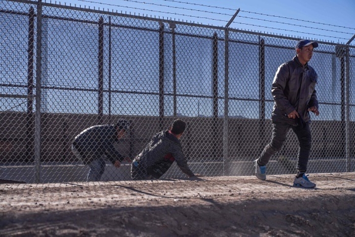 Migrants illegally cross into the US via a hole in a fence in El Paso, Texas, on December 22, 2022.  (Photo by ALLISON DINNER/AFP via Getty Images)