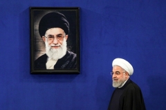 Iranian President Hassan Rouhani walks past a portrait of supreme leader Ayatollah Ali Khamenei. (Photo by Atta Kenare/AFP via Getty Images)