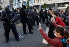 Protesters kneel and hold up their hands in front of a row of police officers in riot gear at a park across from the White House on June 1, 2020 in Washington, DC. (Photo by Olivier DOULIERY/AFP via Getty Images)