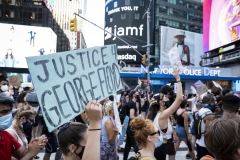 A protester holds a sign that says, "Justice for George Floyd" as the crowd of hundreds pass the New York Police Dept office in Times Square New York in support of black women. (Photo credit: Ira L. Black/Corbis via Getty Images)