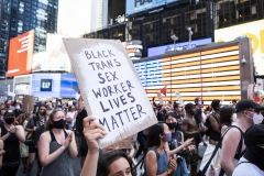 A protester holds a sign that says, "Black Trans Sex Worker Lives Matter" as the crowd of hundreds pass the Jumbotron of the American Flag in Times Square New York. (Photo credit: Ira L. Black/Corbis via Getty Images)