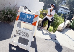 A woman walks past a social distancing sign in Los Angeles, Calif. (Photo credit: David Livingston/Getty Images)