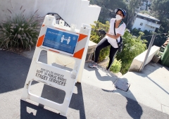 A woman walks past a social distancing sign during the coronavirus pandemic. (Photo credit: David Livingston/Getty Images)