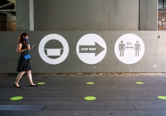 A woman wearing a face mask walks past a social distancing sign. (Photo credit: Noam Galai/Getty Images)