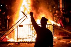 A protester raises a fist near a fire during a demonstration outside the White House over the death of George Floyd at the hands of Minneapolis Police. (Photo credit: SAMUEL CORUM/AFP via Getty Images)