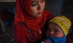 A Uyghur mother and baby at a night market in Xinjiang region. (Photo by Greg Baker/AFP via Getty Images)