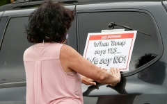 A woman puts a sign on her car prior to the Occupy City Hall Protest and Car Caravan hosted by Chicago Teachers Union in Chicago, Illinois, on Aug. 3, 2020. (Photo credit: KAMIL KRZACZYNSKI/AFP via Getty Images)