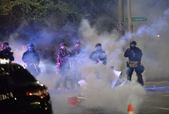 Law enforcement officers stand in a cloud of tear gas in Portland, Oregon on July 26, 2020, as sometimes violent protests continue across the United States. (Photo by ANKUR DHOLAKIA/AFP via Getty Images)