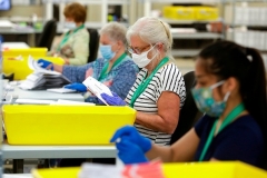 Election workers wear masks and gloves as they open envelopes containing vote-by-mail ballots for the August 4 Washington state primary at King County Elections in Renton, Washington on August 3, 2020. (Photo by Jason Redmond/AFP via Getty Images)