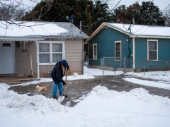 A Waco, Texas, resident clears snow from his driveway alongside his dog on February 17, 2021 as severe winter weather conditions over the last few days has forced road closures and power outages over the state. (Photo by MATTHEW BUSCH/AFP via Getty Images)