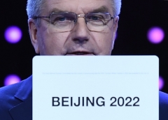 At an International Olympic Committee meeting in 2015, IOC president Thomas Bach shows the card with the winning bid for the Winter Olympic host city for 2022. (Photo by Manan Vatsyayana/AFP via Getty Images)