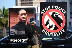 Featured are police brutality protest signs featuring George Floyd and a police officer. (Photo credit: ROBYN BECK/AFP via Getty Images)