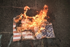 An American flag burns on the ground. (Photo credit: Diego Cuevas/Vizzor Image/Getty Images)