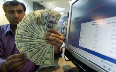 A man holds numerous dollar bills. (Photo credit: AAMIR QURESHI/AFP via Getty Images)