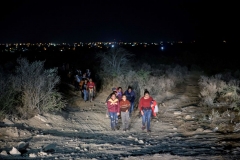 In a photo taken on March 27, 2021 immigrants, who arrived illegally across the Rio Grande river from Mexico, make their way along a track towards a processing checkpoint set up by border patrol agents in the border city of Roma. (Photo by ED JONES/AFP via Getty Images