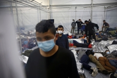 Young children stand as other rest inside a pod at the Donna Department of Homeland Security holding facility, the main detention center for unaccompanied children in the Rio Grande Valley run by the Customs and Border Patrol (CBP), in Donna, Texas on March 30, 2021. (Photo by DARIO LOPEZ-MILLS/POOL/AFP via Getty Images)