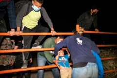 Migrants scale a cattle fence on private property after arriving on the American shores of the Rio Grande River on April 24, 2021 in Roma, Texas. Guided by coyotes piloting an inflatable raft, migrants cross the Rio Grande River and arrive on American soil. After crossing onto the shallow banks, the migrants hike half a mile through sandy gullies and shrub covered land towards waiting Border Patrol officers for processing and detention. (Photo by Benjamin Lowy/Getty Images)