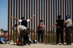 US Border Patrol agents check and search migrants from Guatemala after they turned themselves over to authorities at the US-Mexico border May 12, 2021 in Yuma, Arizona. (Photo by RINGO CHIU/AFP via Getty Images)