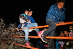 Migrants scale a cattle fence on private property after arriving on the American shores of the Rio Grande River on April 24, 2021 in Roma, Texas. Guided by coyotes piloting an inflatable raft, migrants cross the Rio Grande River and arrive on American soil. (Photo by Benjamin Lowy/Getty Images)