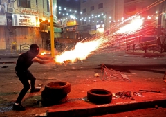 A Palestinian launches flares amid clashes with Israeli soldiers in the city center of Hebron. (Photo credit: HAZEM BADER/AFP via Getty Images)