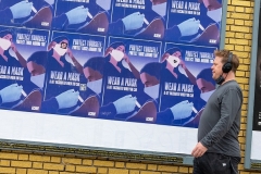 A man without a mask walks past signs that read "protect yourself, protect those around you, wear a mask and get vaccinated when you can" in Los Angeles on April 22, 2021. (Photo by Alexi Rosenfeld/Getty Images)