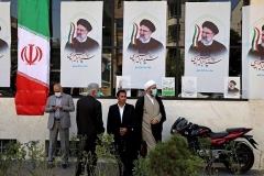 Iranians stand in front of a campaign office displaying posters for presidential candidate Ebrahim Raisi in Tehran. (Photo by Atta Kenare/AFP via Getty Images)