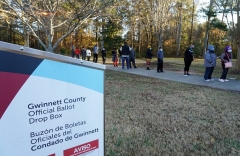 Behind the ballot drop box, voters wait in line to vote in person in Atlanta, Georgia. (Photo by TAMI CHAPPELL/AFP via Getty Images)