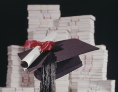 A graduation cap is displayed against stacks of money. (Photo credit: Harold M. Lambert/Contributor/Getty Images)
