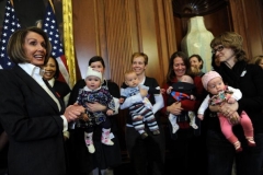 Speaker of the House Nancy Pelosi poses with mothers and their babies during a healthcare reform event in 2010. (Photo by TIM SLOAN/AFP via Getty Images)