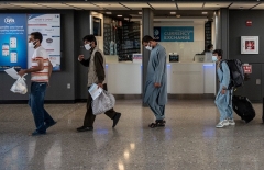 Afghan evacuees are escorted to a waiting bus after arriving at Dulles International Airport in Chantilly, Virginia on August 23, 2021. (Photo by ANDREW CABALLERO-REYNOLDS/AFP via Getty Images)