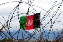 Afghanistan’s national flag flies behind barbed wire at a military base in Nangarhar province in 2014.  (Photo by Roberto Schmidt/AFP via Getty Images)