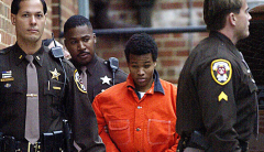 This Dec. 4, 2002 file photo shows then sniper suspect Lee Boyd Malvo (C) leaving a pre-trial hearing at the Fairfax County Juvenile and Domestic Relations Court in Fairfax, Va. (Photo credit: LUKE FRAZZA/AFP via Getty Images)