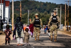 US Military Police walk past Afghan refugees at the Ft. McCoy US Army base on September 30, 2021 in Ft. McCoy, Wisconsin. (Photo by BARBARA DAVIDSON/POOL/AFP via Getty Images)