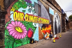 Street artists paint a mural on a wall opposite the COP26 climate summit venue in Glasgow on October 13, 2021. (Photo by ANDY BUCHANAN/AFP via Getty Images)