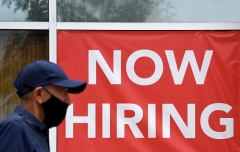 A man walks by a "Now Hiring" sign outside a store in Arlington, Virginia in August 2021. (Photo by OLIVIER DOULIERY/AFP via Getty Images)