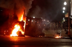 Kenosha police officers in riot gear form a line behind a burning truck during violent demonstrations against the shooting of Jacob Blake in Kenosha, Wisconsin on August 24, 2020. (Photo by KAMIL KRZACZYNSKI/AFP via Getty Images)