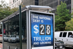 A sign at bus stop in Washington, D.C., shows the amount of the U.S. national debt, which increases every second. (Photo by JULIE CHABANAS/AFP via Getty Images)