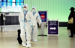 A flight crew from Air China arrives at Los Angeles International Airport in hazmat suits on December 3, 2021, as Los Angeles County reported its first case of the omicron variant. (Photo by FREDERIC J. BROWN/AFP via Getty Images)