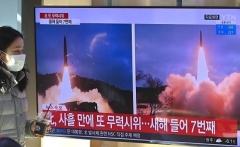 A woman in Seoul walks past a television screen on Sunday showing a news broadcast with file footage of a North Korean missile test. (Photo by Jung Yeon-Je/AFP via Getty Images)