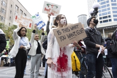 Erica Corbin, 31, of Tacoma, wearing a bloody gown, holds a hanger, a symbol of the reproductive rights movement, and a sign that reads "is this what you want GOP?" during a "Rally to Defend Roe v. Wade" and "Stand up for Abortion and LGBTQ Rights" event in Seattle, Washington on May 3, 2022. (Photo credit: JASON REDMOND/AFP via Getty Images)