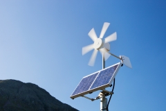 A solar electric panel and wind turbine being used to power a neon road sign. (Photo credit: Ashley Cooper/Construction Photography/Avalon/Getty Images)