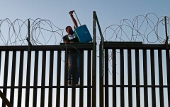 Migrants attempt to illegally cross a fence into the U.S. from Mexico in San Luis, Arizona. (Photo by Nick Ut/Getty Images)