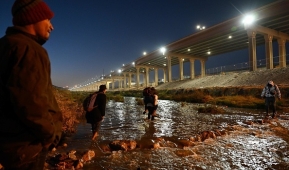 Migrants are carried across the Rio Grande river into El Paso, Texas on December 19, 2022. (Photo by PATRICK T. FALLON/AFP via Getty Images)