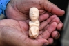 A model of a fetus is held. (Photo credit: JOAQUIN SARMIENTO/AFP via Getty Images)